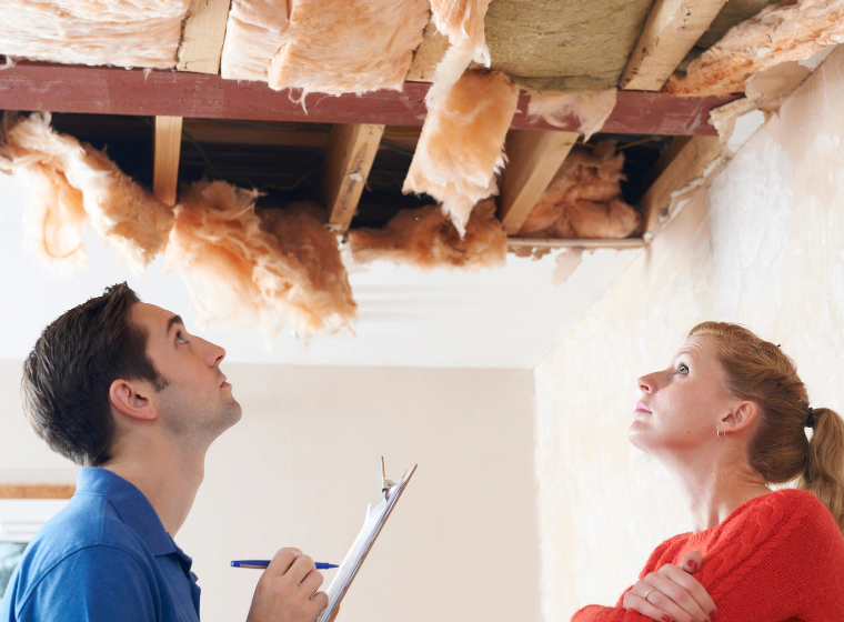 an inspector checking a damaged ceiling